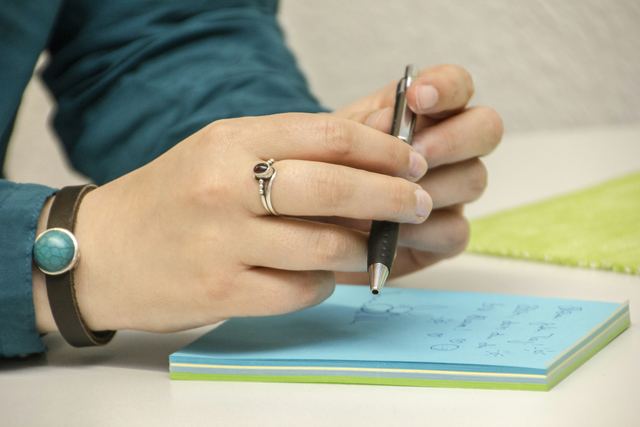 Pessoa escrevendo com caneta em um bloco de notas