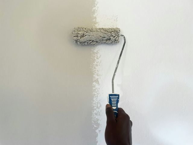 Pintor passando tinta numa parede com um rolo