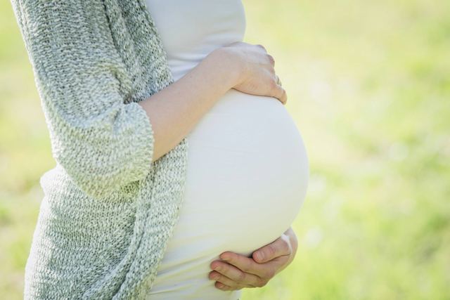 Mulher grávida com as mãos sobre a barriga