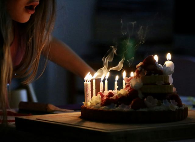 Mulher de regata branca segurando velas de aniversário acesas