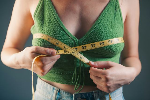Mulher medindo a cintura com uma fita métrica.
