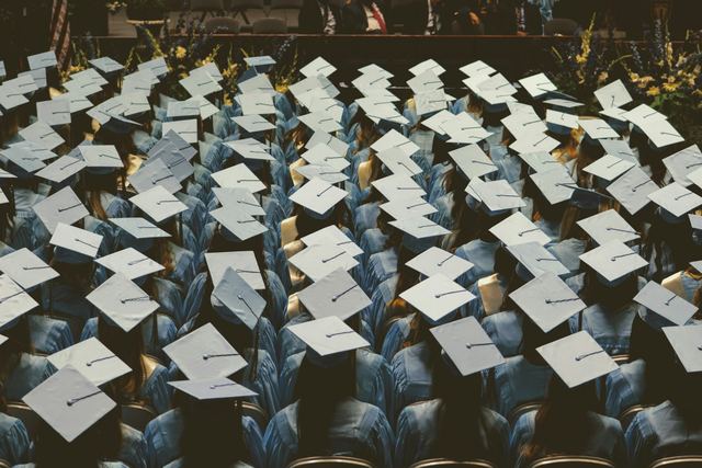 Grupo de formandos com becas azul-claras e capelos em uma cerimônia de formatura