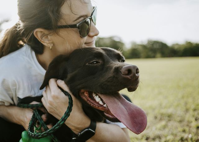 Mulher abraçando um cachorro, com o rosto encostado nele.