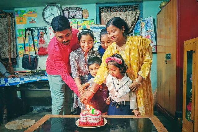 Família reunida cortando junta um bolo de aniversário com velas