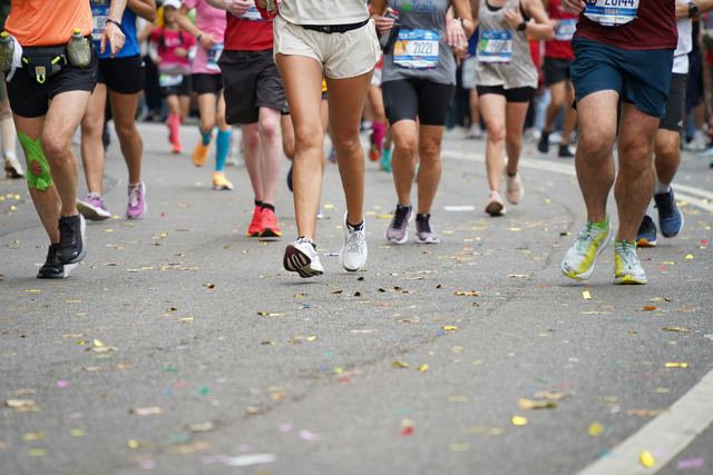 Grupo de corredores de maratona correndo por uma avenida do Central Park.
