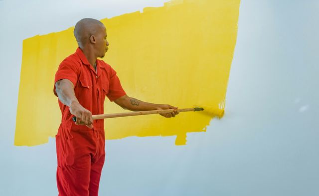 Pintor de uniforme trabalhando numa parede dentro de casa, no preparo do revestimento