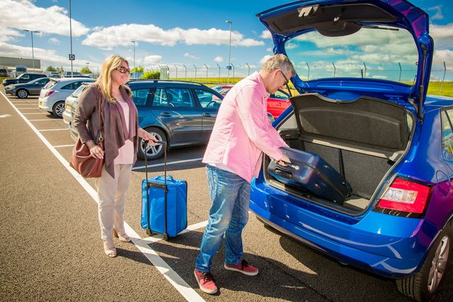 Casal colocando as malas no porta-malas do carro antes de pegar a estrada