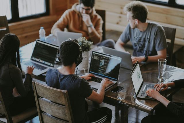Grupo de colegas reunidos em volta de notebooks trabalhando juntos