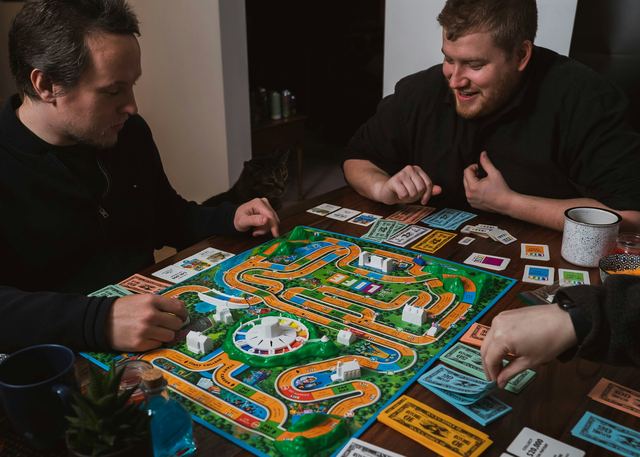 Dois homens jogando um jogo de tabuleiro sobre uma mesa.