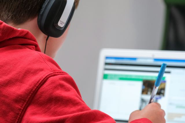Jovem de fones de ouvido estudando em um notebook em casa