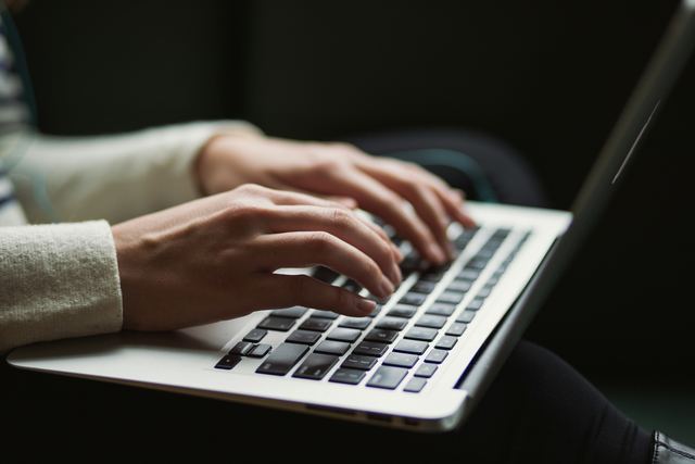 Pessoa de costas usando um notebook, lendo o que aparece na tela