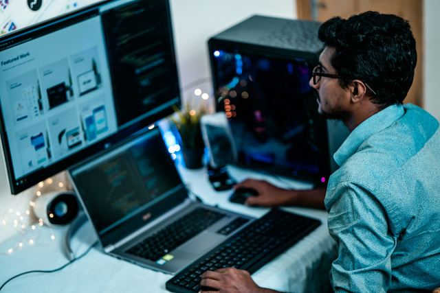 Homem de camisa azul trabalhando no computador em uma mesa organizada