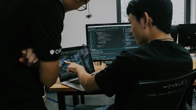 Dois homens trabalhando em computadores num escritório