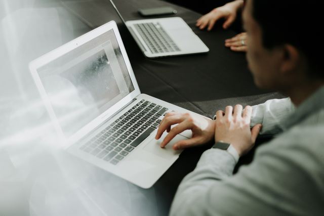 Homem sentado diante de um notebook em uma mesa de trabalho