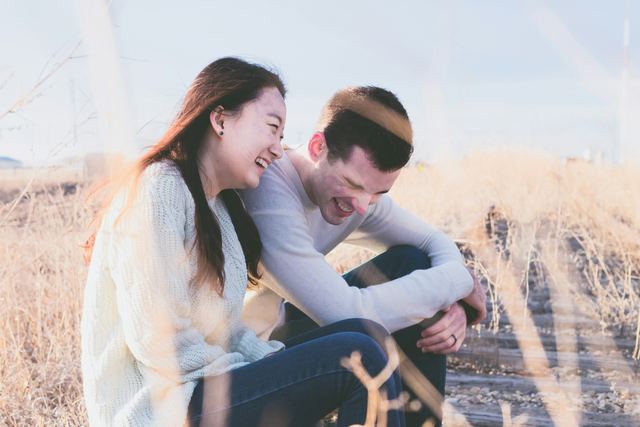 Um homem e uma mulher rindo juntos ao ar livre durante o dia.