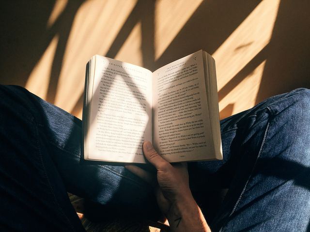 Pessoa sentada segurando um livro aberto nas mãos