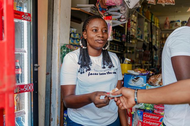 Comerciante sorrindo ao receber o pagamento de um cliente no balcão da loja