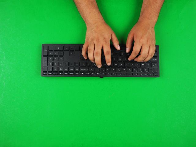 Pessoa digitando num teclado de computador, vista de perto das mãos