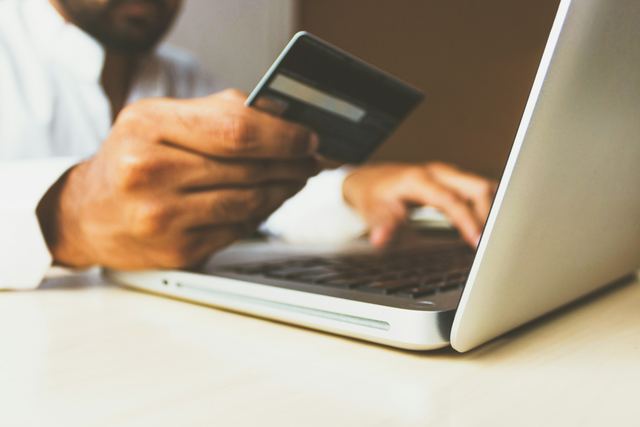Homem usando um notebook enquanto segura um cartão de crédito