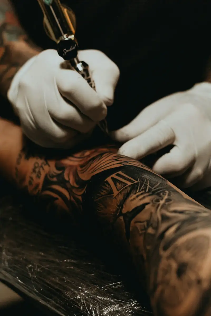 Máquina de tatuagem fazendo sombreado em um braço já fechado de tatuagens